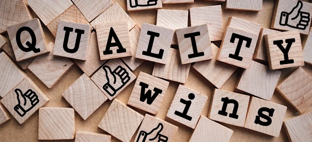 Wooden letter tiles spelling “Quality Wins” with thumbs-up icons scattered around