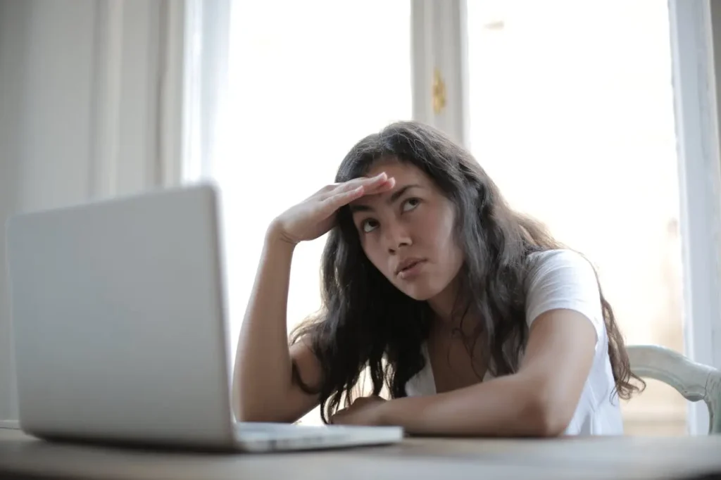 A stressed woman looking overwhelmed while researching property prices and legal fees on her laptop.
