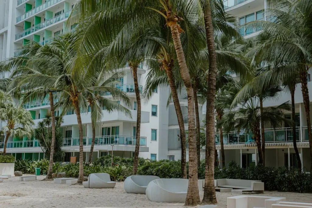 White sand man-made beach with palm trees at a luxury condominium pool area in Malaysia.