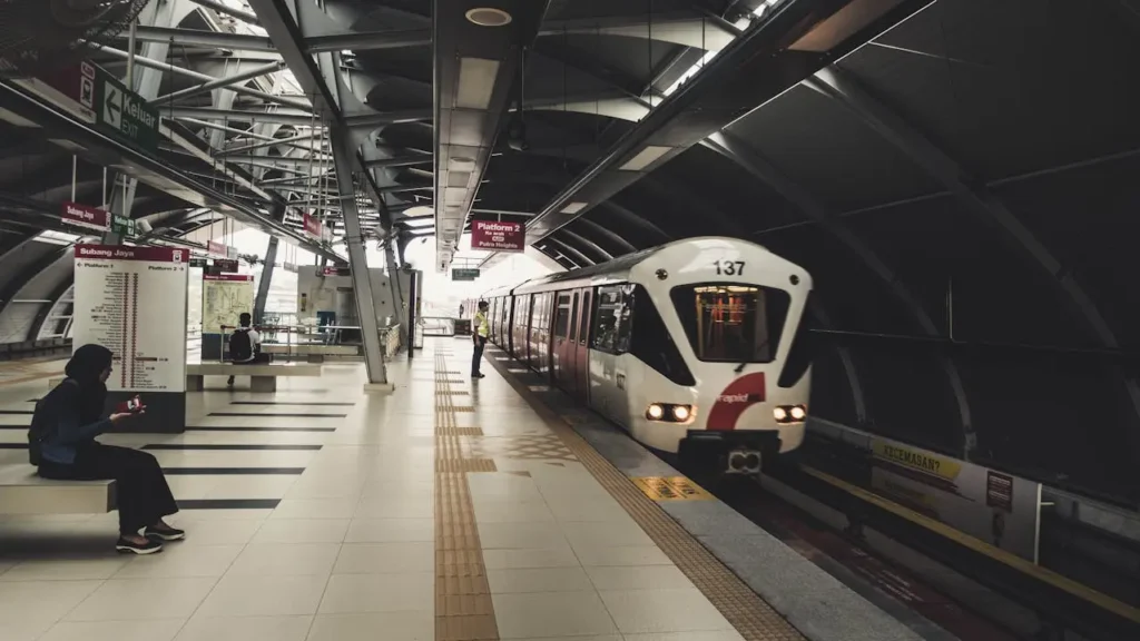 A RapidKL train pulling into the platform at the Subang Jaya LRT station during the day.