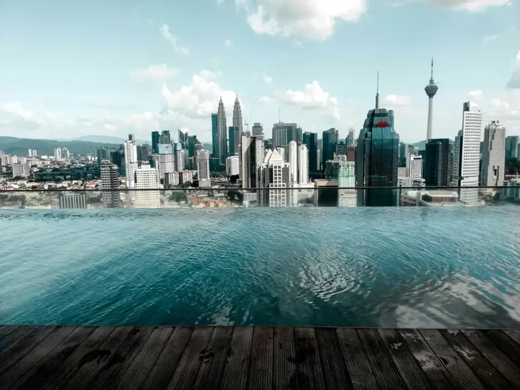 View from a rooftop infinity pool overlooking the Kuala Lumpur skyline and KL Tower, representing luxury facilities in Malaysian high-rises.